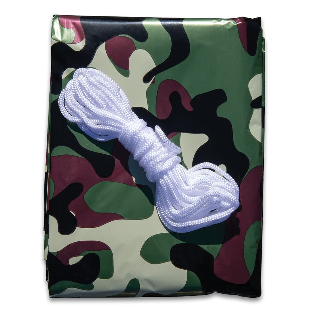 Full image of the AdventureGuard Camo Emergency Shelter folded with the string sitting on top. image number 1